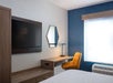 One king bed, flat-screen TV, and desk with chair inside a guest room.
