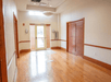 An empty room with wooden flooring and white walls, a closet on the right, and a glass door leading outside.