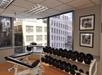 A fitness center with free weights and a bench along a wall with large windows with a view of the city in Denver, Colarado.