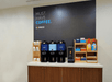 A coffee bar with cups on the left, creamers and sugars on the right, and three dispensers of coffee in the middle.