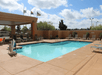 Outdoor swimming pool area with lounge chairs and flags in the background, under a partly cloudy sky.