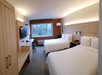 Guest room with two queen beds, seating area, work desk, and flat-screen TV.