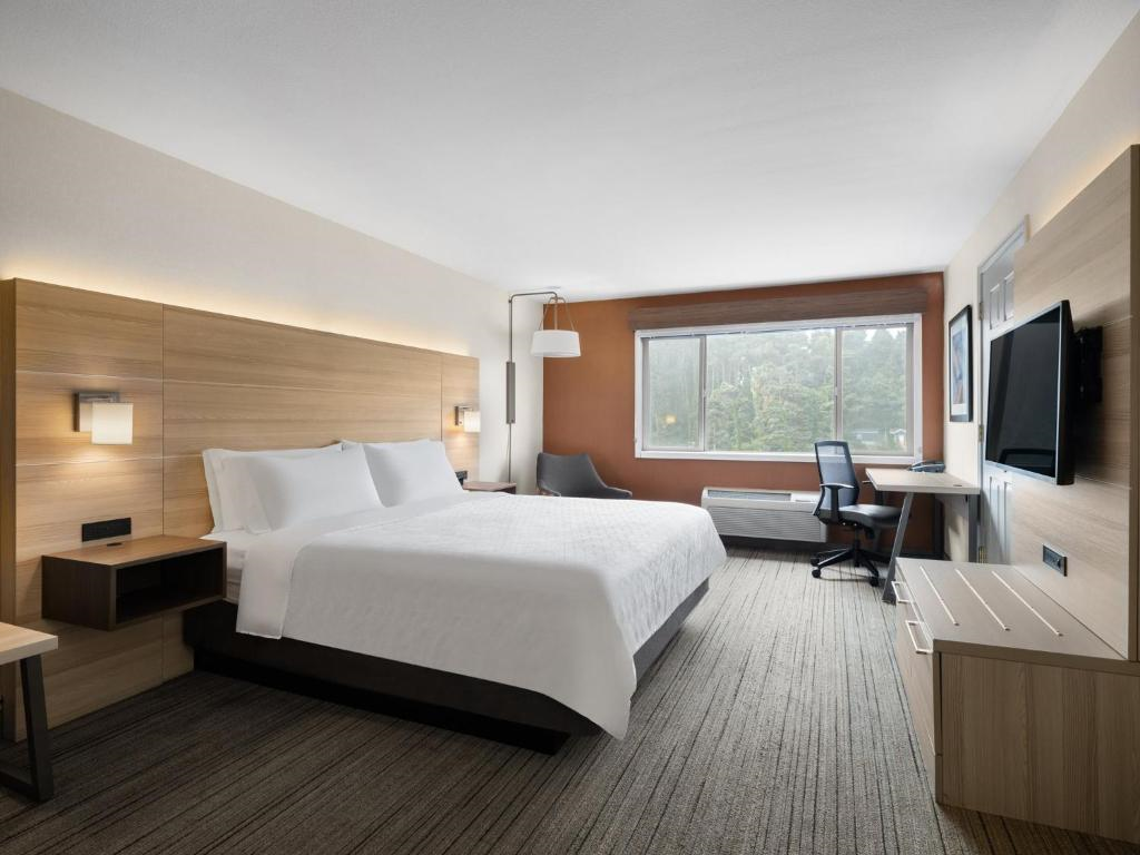 Guest room with one king bed, seating area, work desk, and flat-screen TV.