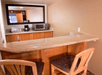 Small kitchenette with a counter, two wooden chairs, a coffeemaker, microwave, and dish rack. Mirror on the wall reflects part of the room.