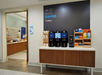 A coffee station with multiple coffee dispensers, cups, and condiments, next to a breakfast area entrance.