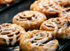 Close-up of freshly baked cinnamon rolls drizzled with icing on a baking tray.