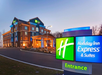 Exterior view of a Holiday Inn Express & Suites hotel with illuminated signage at dusk.