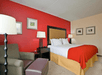 Cozy guest room featuring a king bed, armchair, and ottoman for ultimate relaxation.