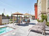 Outdoor pool with sun loungers and tables with umbrellas.