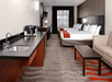 Two beds, seating area, and wet bar inside a guest room.