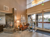 Hotel lobby with a modern fireplace, brown sofa, glass coffee table, and glass entrance doors. Warm lighting creates a welcoming atmosphere.
