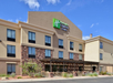 Three-story hotel exterior with a stone facade and wood-accented entrance, featuring the Holiday Inn Express & Suites logo on the building.