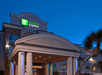The front exterior and covered entrance of the Holiday Inn Express Las Vegas at night with the green and white sign shining bright.