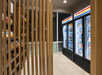 Small convenience store section with wooden shelves on the left holding snacks, and illuminated refrigerated display cases on the right containing drinks and packaged foods.