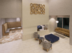 Hotel lobby with beige tiles, a seating area featuring two chairs, a blue ottoman, and a sofa. Wall art with circular designs is displayed above. Two additional seating alcoves are visible.