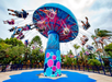 Colorful swing ride with people enjoying the attraction against a backdrop of trees and a cloudy sky.