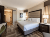 1 King bed, bedside lamps, TV and desk in a guest room.