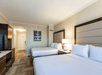 2 Queen beds and bedside lamps in a guest room.