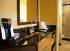 Coffee maker on a wet bar with microwave and mini-fridge.
