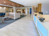 Lobby area with modern furnishings, including a blue reception desk, seating area with chairs and couches, and neutral tile flooring.
