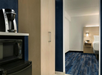 Hotel room featuring a microwave, coffee maker, and bed. Blue carpet and wood cabinets are visible.