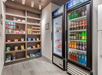 A small shop with shelves of snacks and two refrigerated displays holding beverages and chilled foods.