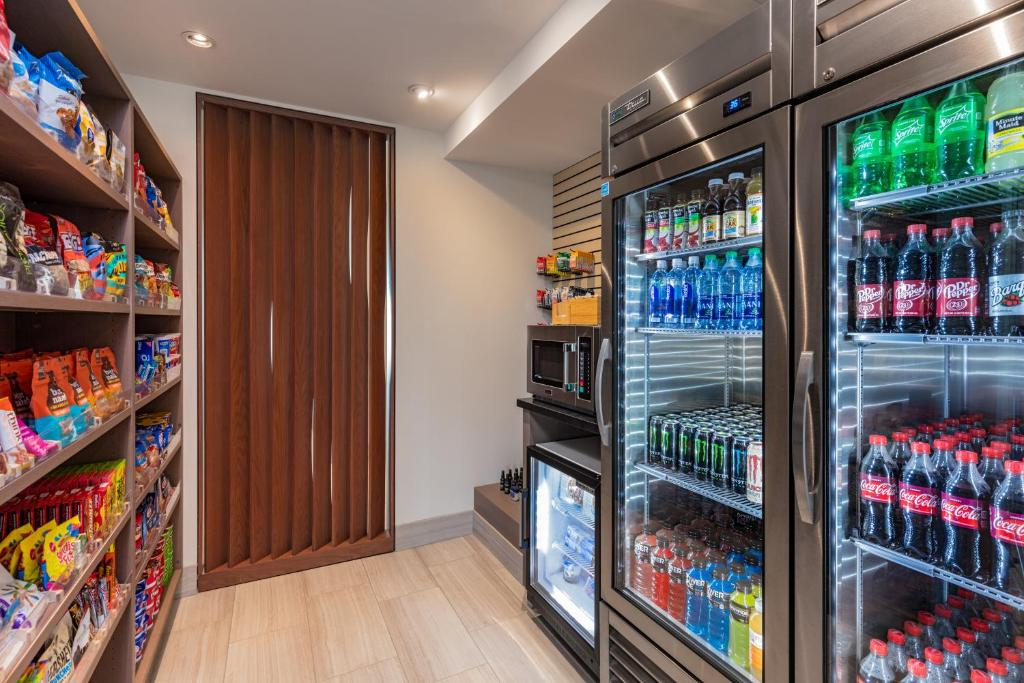 Small convenience store with shelves of snacks and refrigerated beverages, including soda and water. A microwave sits between the snack display and refrigerators.