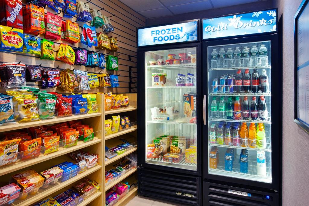 Snack and beverage corner with shelves of chips and two refrigerators; one labeled "Frozen Foods" with ice cream and meals, the other "Cold Drinks" with assorted sodas and beverages.