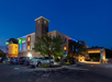 Exterior view of a Holiday Inn Express hotel at dusk, with cars parked in the lot and illuminated signage on the building.
