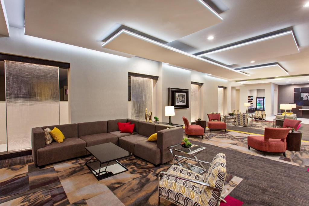 Modern hotel lobby with a mix of brown and red seating, a patterned carpet, and contemporary lighting.