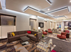 Modern hotel lobby with a mix of brown and red seating, a patterned carpet, and contemporary lighting.