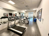 A small gym with exercise equipment, including a treadmill, elliptical, stationary bike, and exercise balls, with large mirrors on the wall.