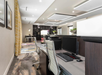 Modern office space with computers, chairs, and decorative elements like plants and artwork. Bright lighting and contemporary design elements are featured throughout.