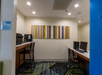 Hotel business center with computers, a printer, and striped artwork on the wall.