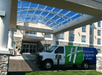 The shuttle for the Holiday Inn Express & Suites Columbus parked under the covered entrance to the hotel on a sunny day.