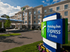 Close up of the blue and green sign for the Holiday Inn Express & Suites with the large hotel in the background on a sunny day in Columbus, Ohio.