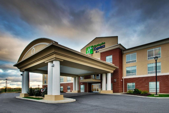 Exterior view of a Holiday Inn Express hotel with a covered entrance and a cloudy sky overhead.