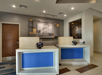 Hotel reception area with two modern desks, blue panels, card readers, and a wall artwork behind.