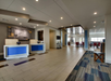 Modern hotel lobby with tiled flooring, two check-in desks, and a seating area.