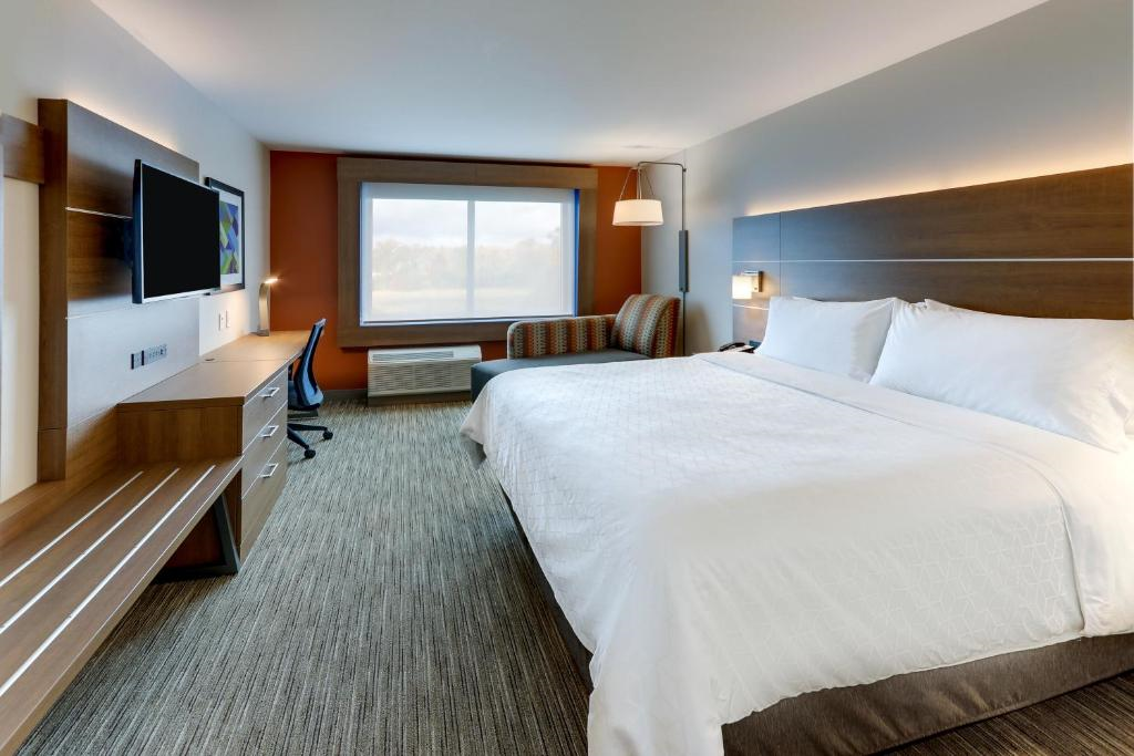 Guest room with one king bed, chaise lounge, work desk, and flat-screen TV.