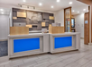 Hotel reception area with two modern desks and illuminated blue panels, backed by a decorative wall panel.