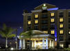 The front entrance to the Holiday Inn Express & Suites at night with lights illuminating the covered walkway in Orlando, Florida.