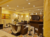 A large lobby with several different seating options in front of a large TV built in to the wall at the Holiday Inn Express & Suites in Orlando, Florida.