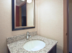 A bathroom sink with a granite countertop and a wall-mounted rectangular mirror.