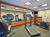 A gym room with treadmills, an exercise bike, mirrored wall, TV, and water cooler.