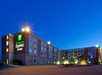 Exterior view of a Holiday Inn Express & Suites hotel at dusk, with illuminated signage and warm lighting.