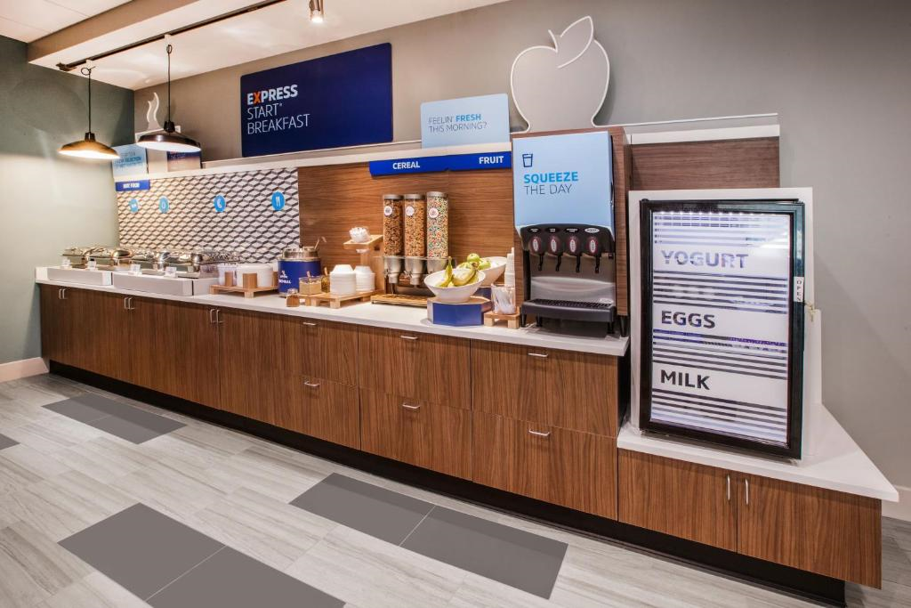 Breakfast buffet with cereal dispensers, fruit display, and a fridge labeled "Yogurt, Eggs, Milk.
