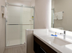 Modern bathroom with a glass-enclosed shower, white countertop sink, and towels neatly hung on the wall.