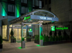 Holiday Inn hotel entrance at night, with illuminated signs and green accent lighting, located at 125 W. 26th Street.