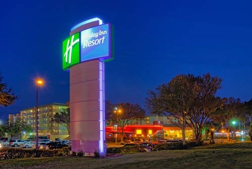 Road sign for the Holiday Inn Resort lit up at night.